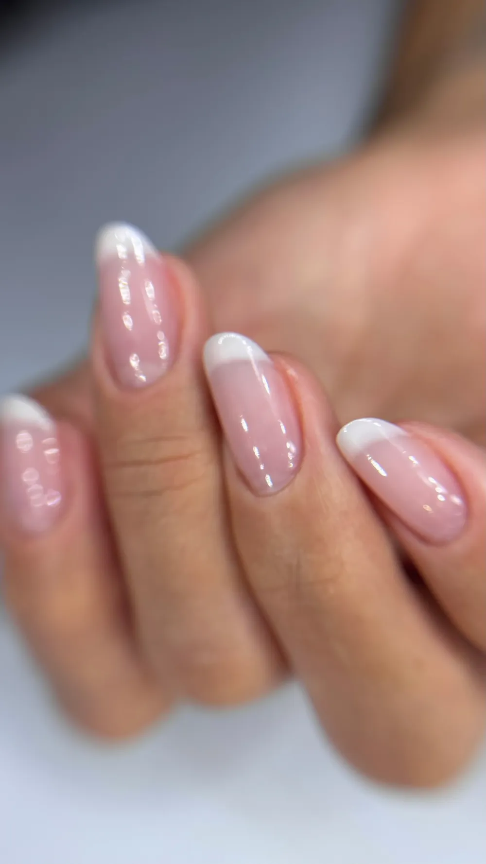 Unhas almond em nude com francesa clean e acabamento glossy, feitas com a técnica LM por Thais Bessa